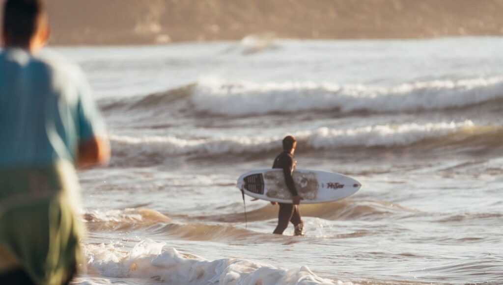 Side view of anonymous man with surfboard watching waves and preparing for practising surfing